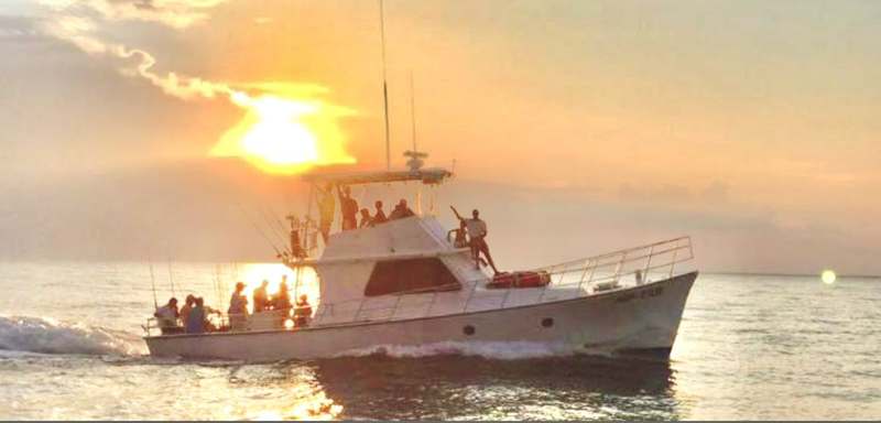 A Riptide charter boat silhouetted against a Gulf Coast sunset