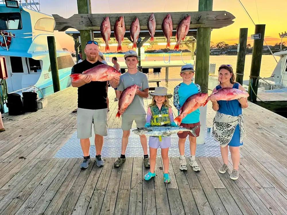 Kids holding red snapper at the dock at sunset