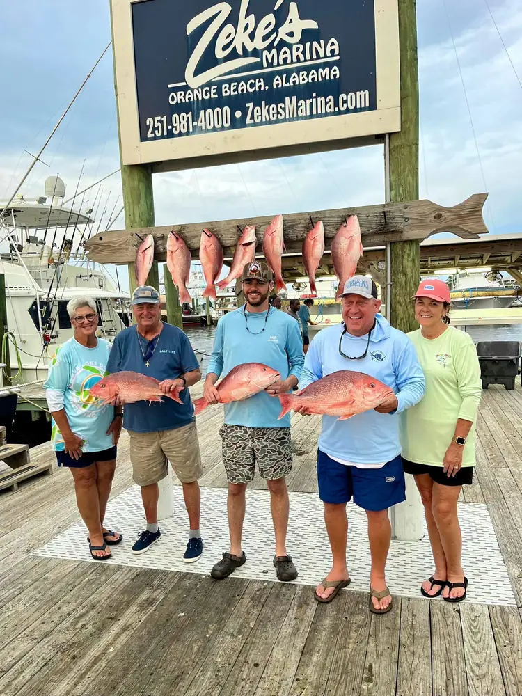 A charter group with snapper under the Zeke's Marina sign
