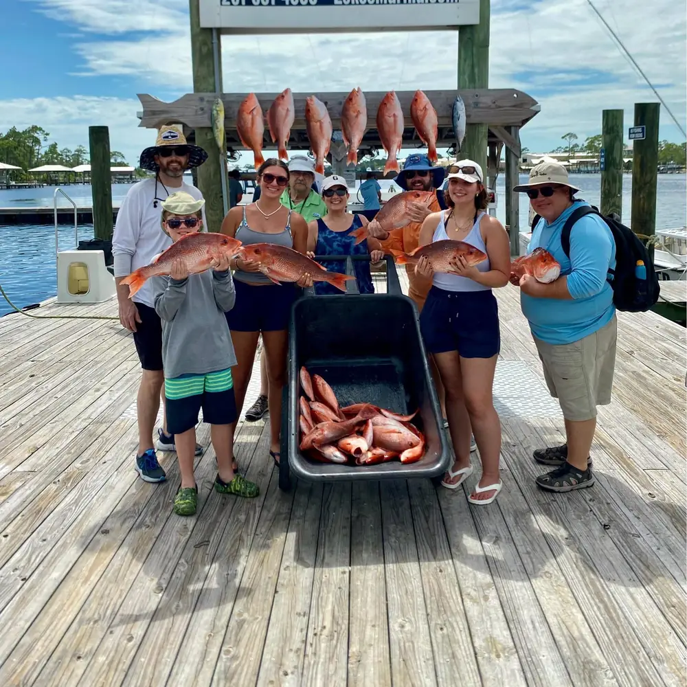 A charter party with a cart of red snapper at the dock