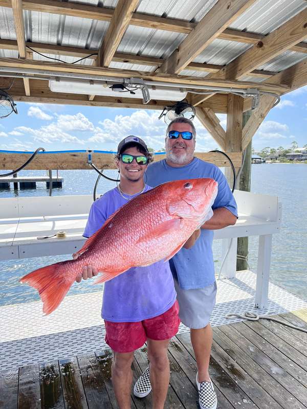 Two anglers with an oversized red snapper at the marina