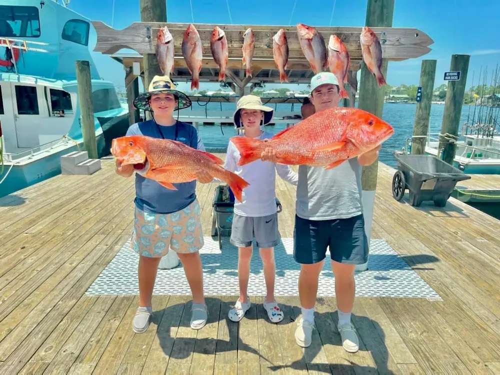 Three guests with their red snapper on the Orange Beach dock