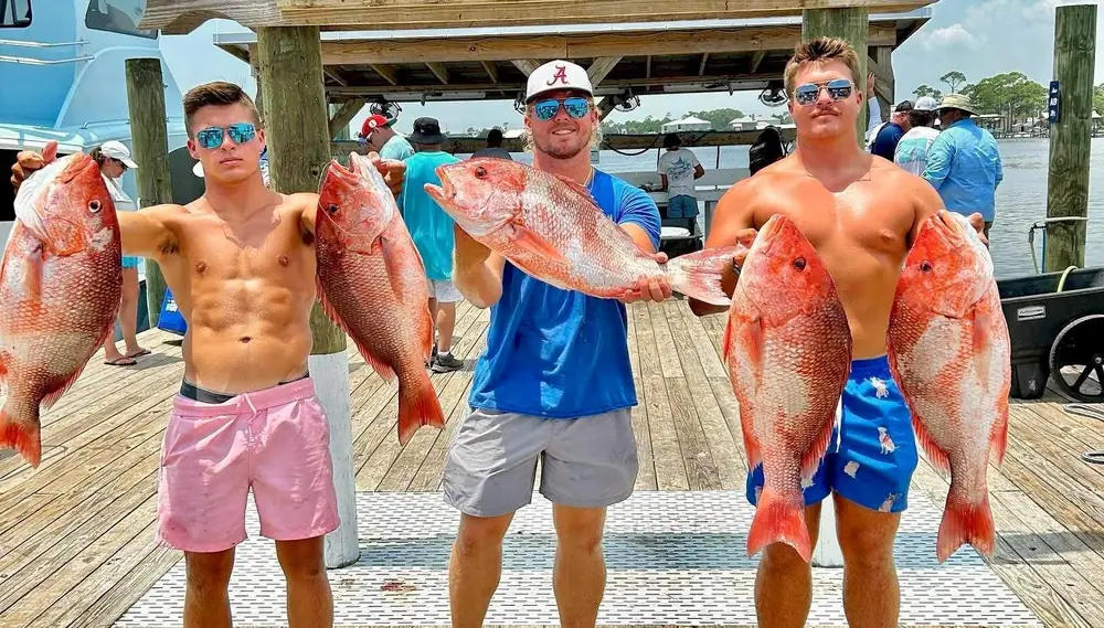 Two anglers holding big red snapper at the fish rack