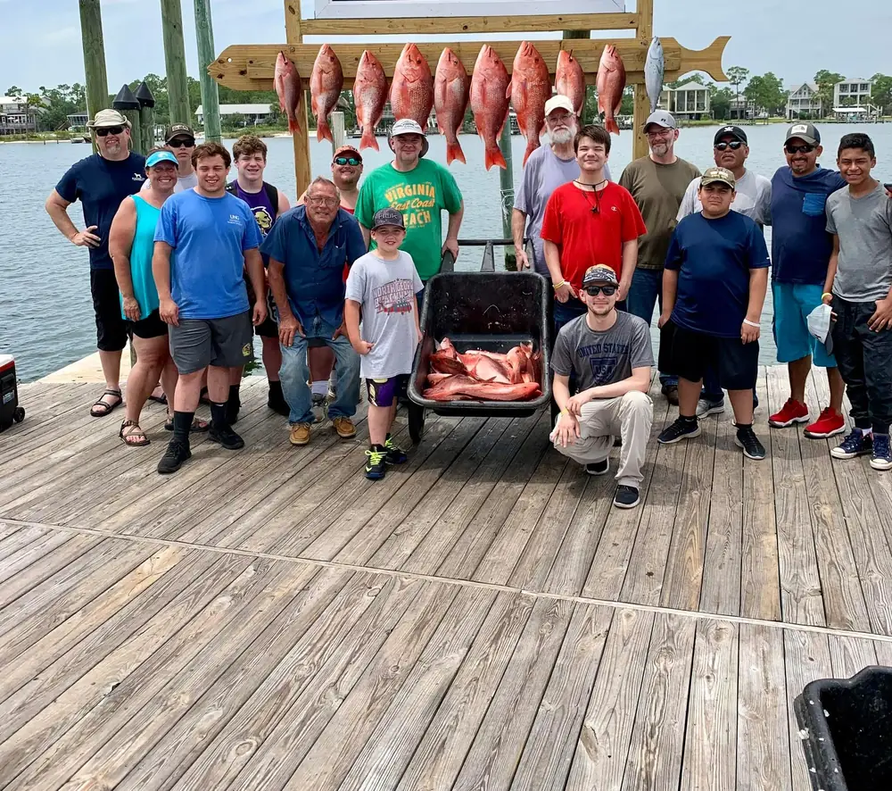 A large charter group with a cart of red snapper