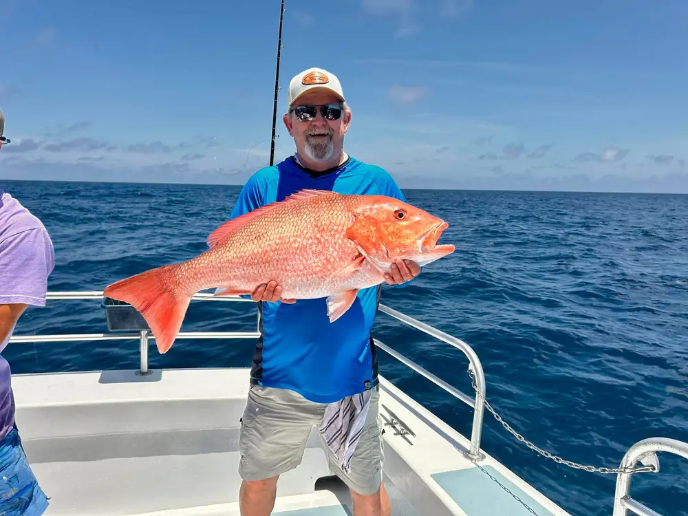 An angler holding a bright red snapper on the Gulf
