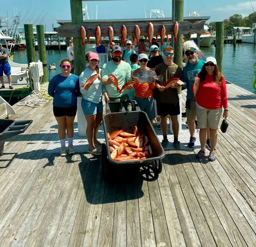 A large party with a cart of red snapper at the marina