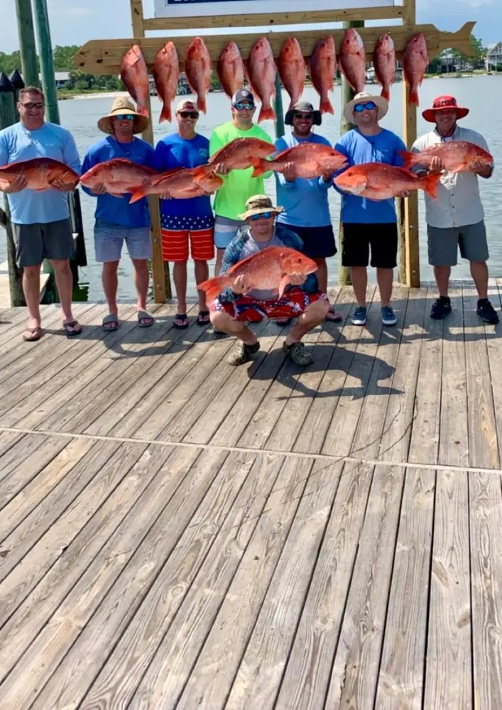 A big charter group lined up with red snapper at the rack