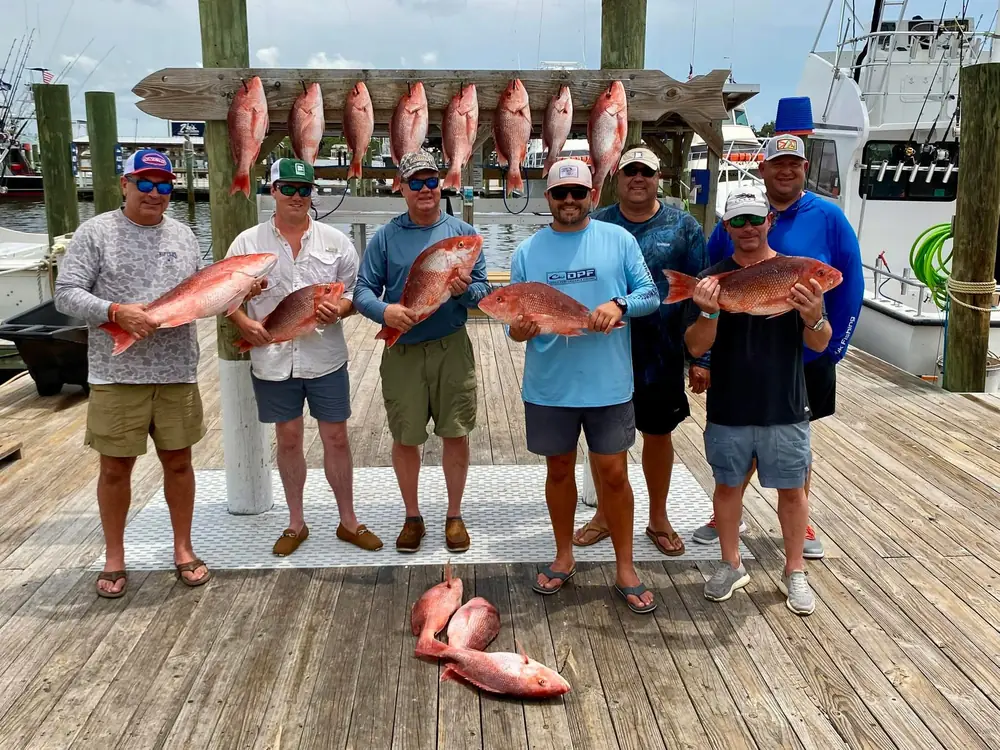 A charter party holding red snapper on the dock