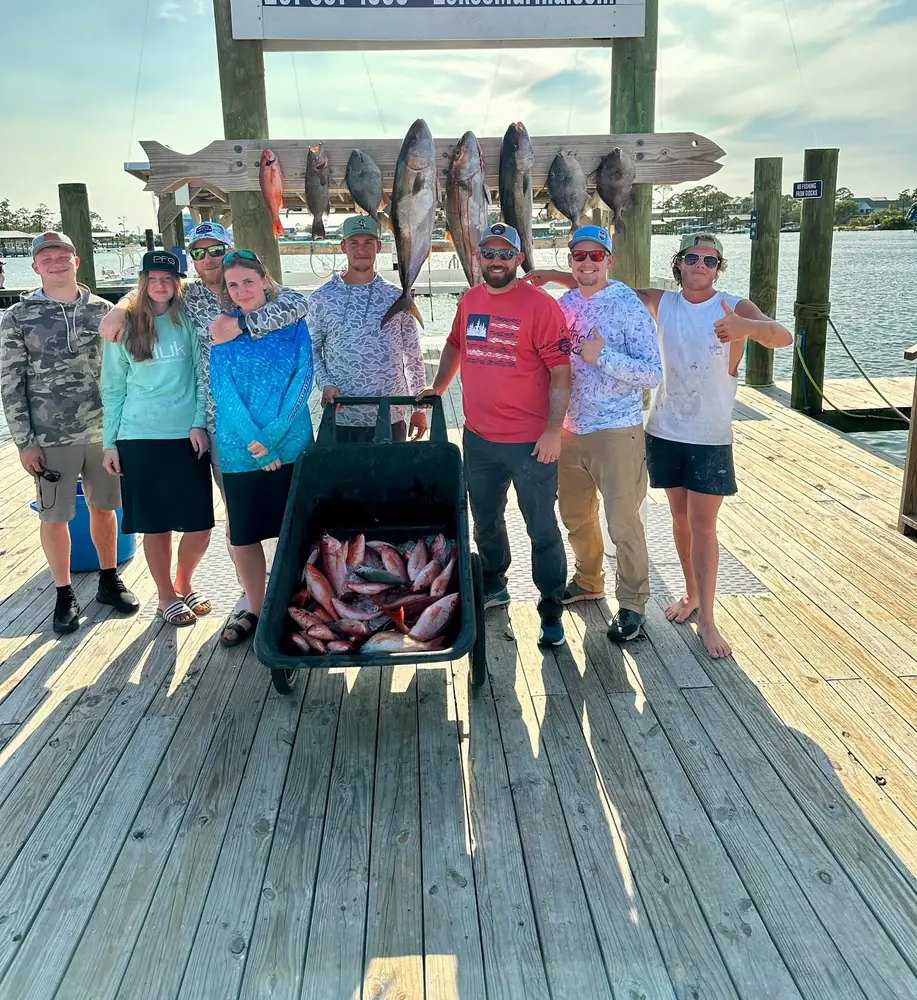 A charter group with a cart of red snapper at the dock