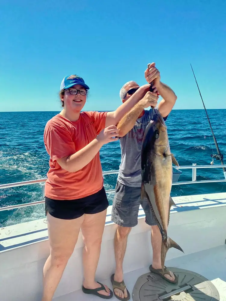 Two guests with a sailfish alongside the boat