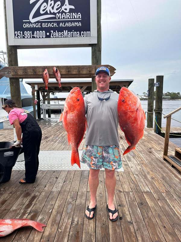 An angler with a matched pair of red snapper at the marina