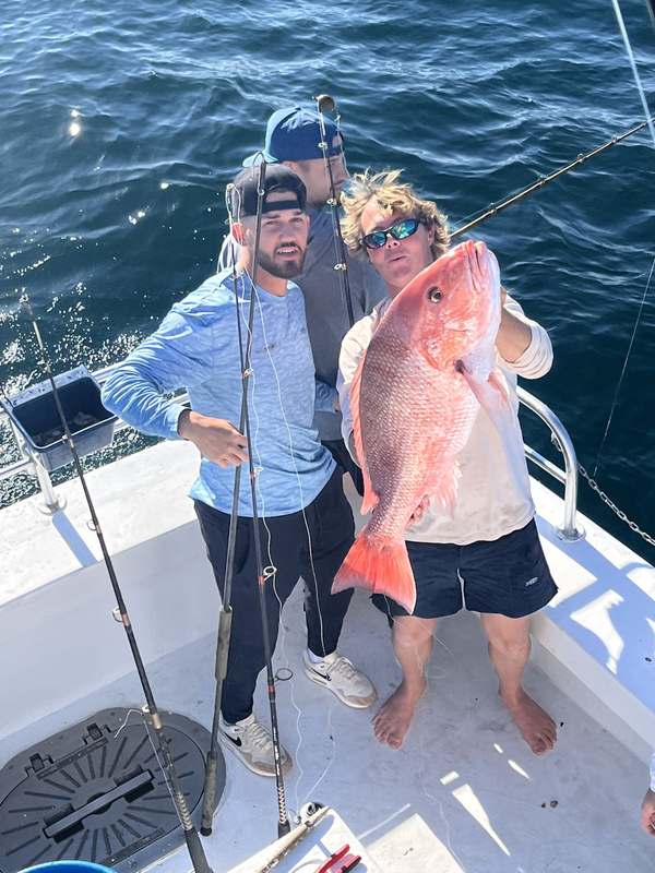 An angler on deck with a red snapper caught bottom fishing