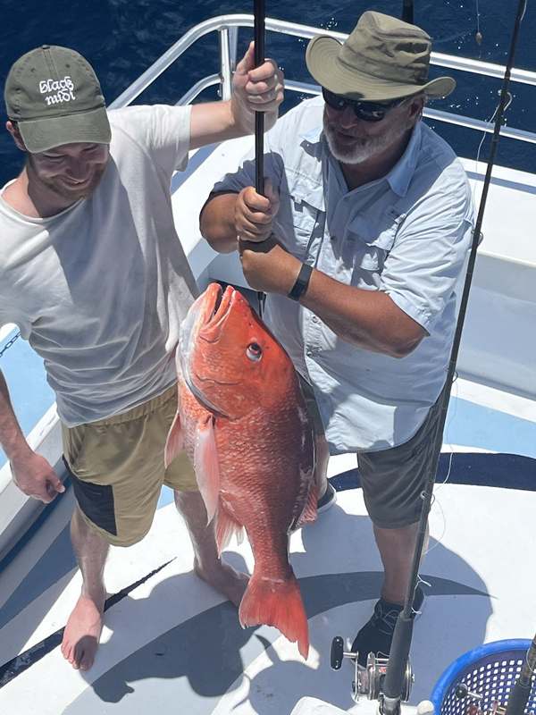 Deckhand and angler hoisting a big red snapper aboard