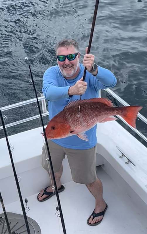 An angler fighting and landing a red snapper on the Rip Tide