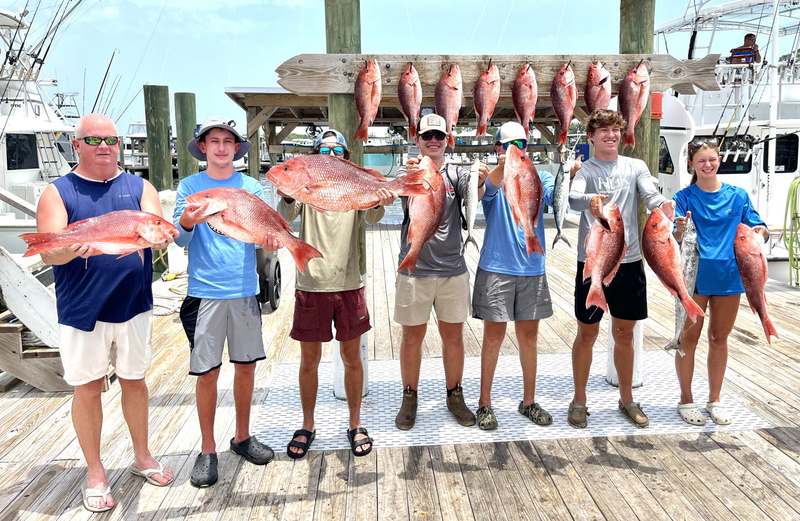 Two anglers holding red snapper on the dock at Zeke's Landing
