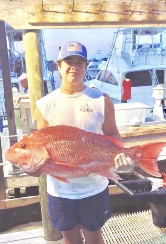 A guest holding a heavy red snapper at the fish-cleaning station