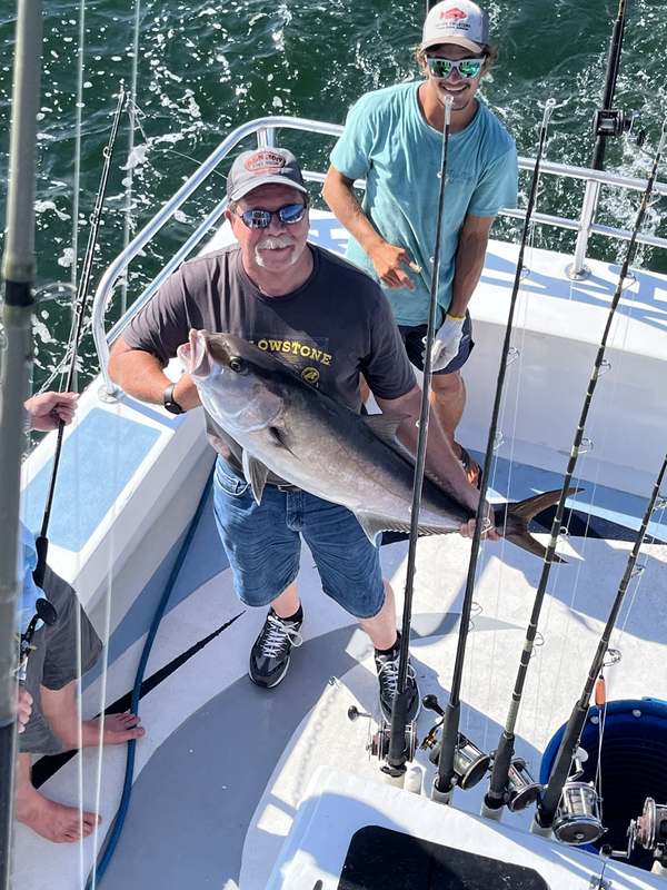 An angler with a strong Gulf amberjack on the back deck
