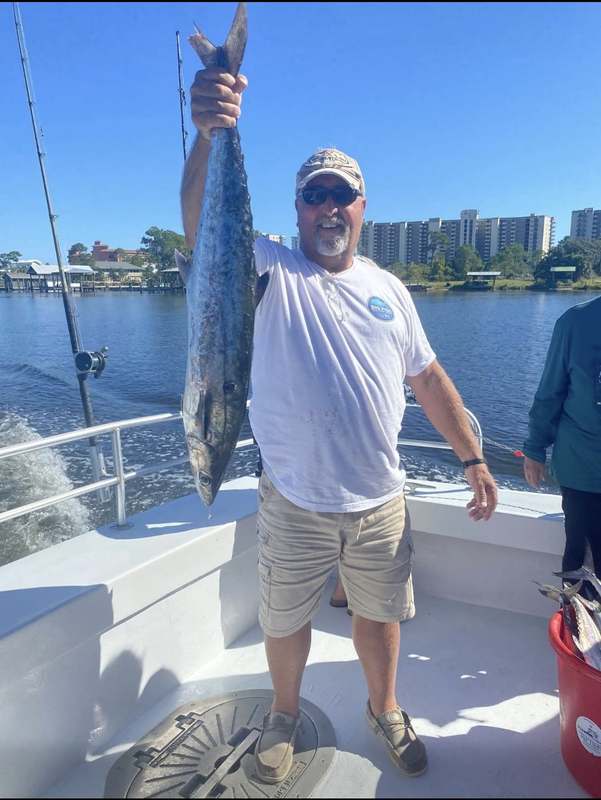 A guest holding a long king mackerel caught trolling near shore