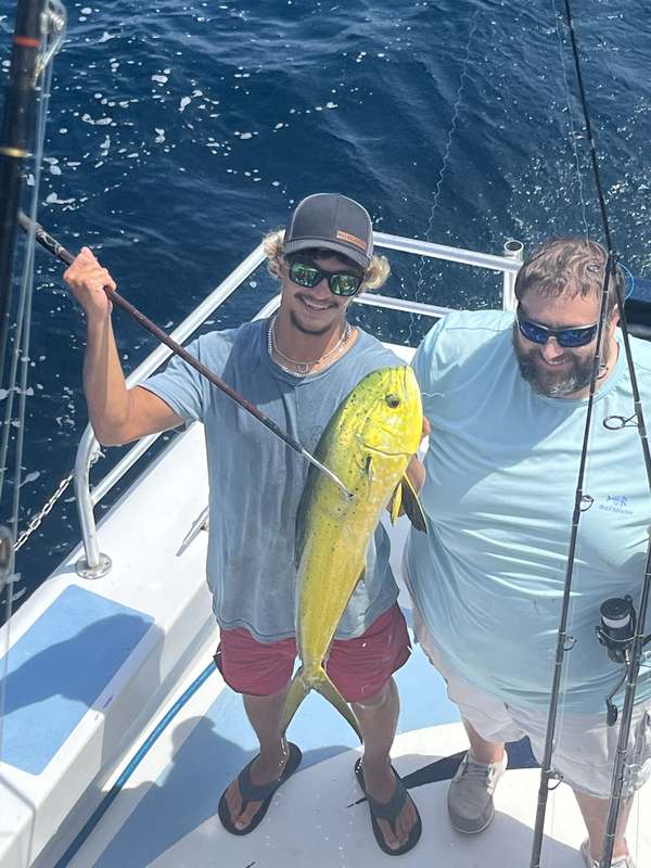 Two anglers with a bright mahi caught on the troll