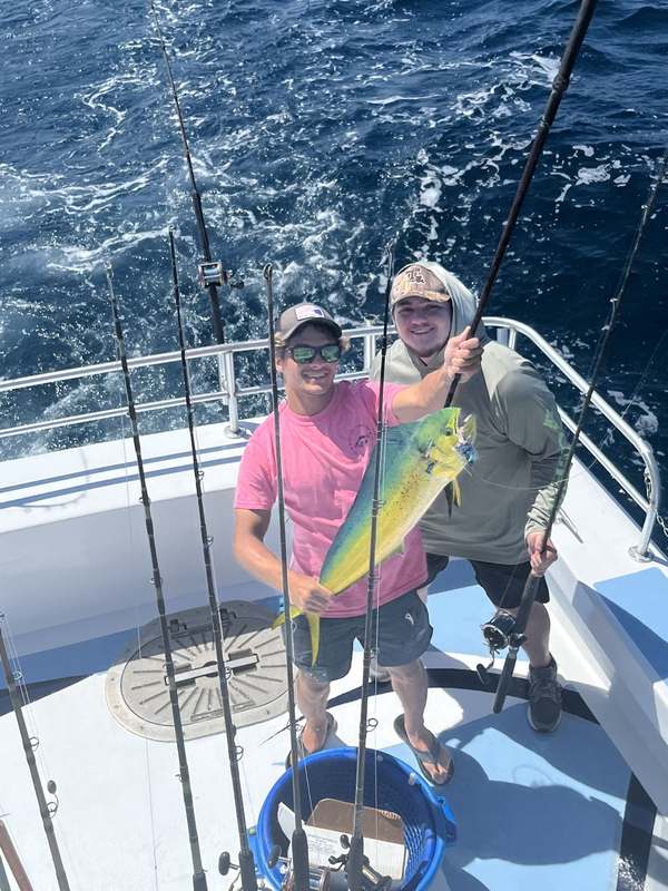 A pair of guests holding a mahi-mahi on the Rip Tide