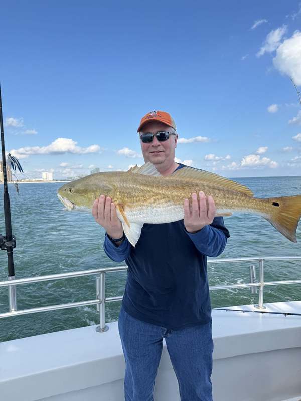 A guest holding a copper-colored redfish on a calm morning