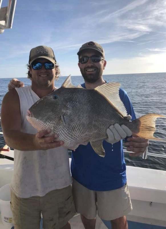 An angler holding a black grouper caught over Gulf structure