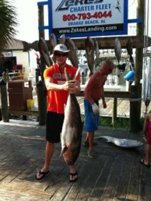 An angler with a long king mackerel at the dock