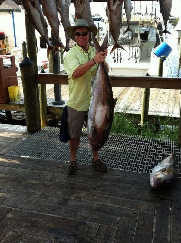 A guest holding an amberjack on the pier at Zeke's Landing