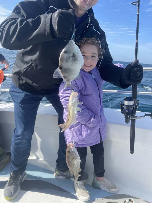 A little girl proudly holding her first triggerfish