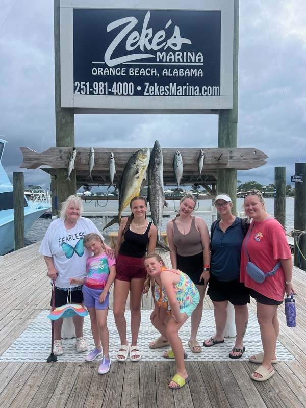A family group with their catch under the Zeke's Landing sign