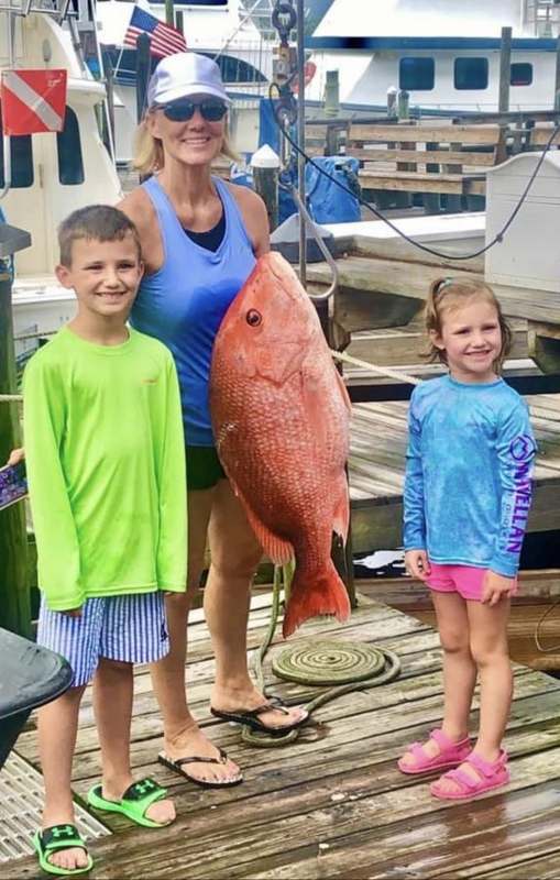 Two children holding a red snapper on the dock