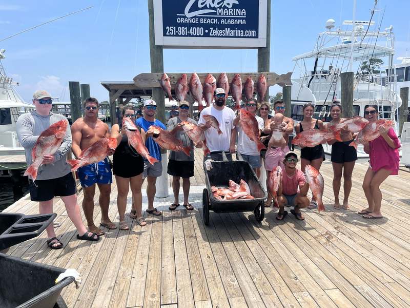 A charter group with a cart of Gulf snapper at the marina