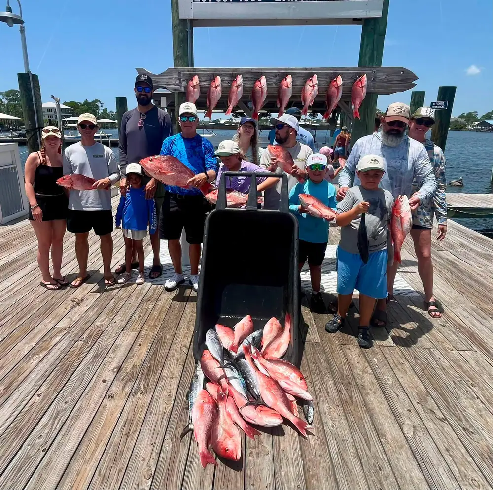 A large charter group with their red snapper and a full cart at the dock