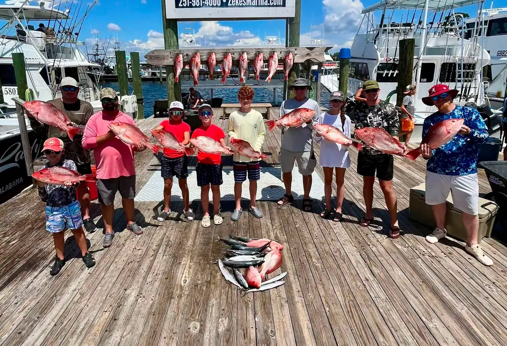 A charter party lined up with red snapper under the fish rack