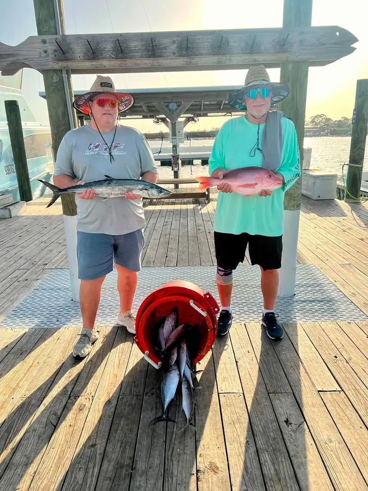 Two anglers with their catch laid out on the dock