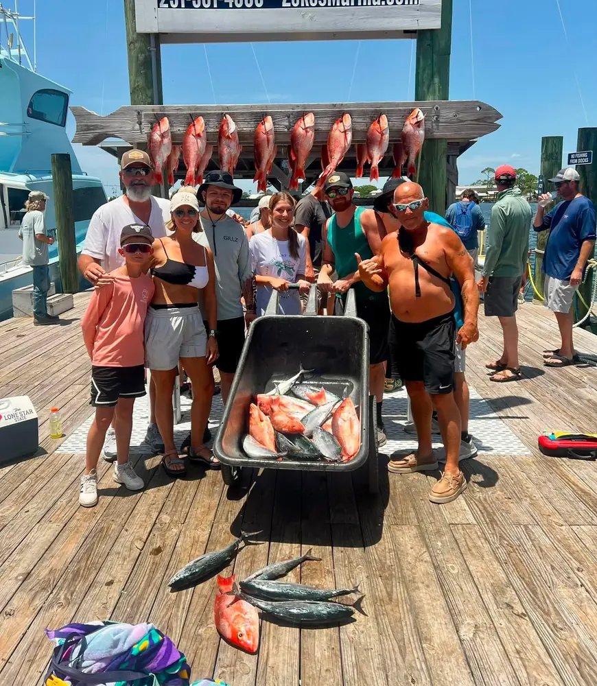 A charter group with a cart of red snapper at the marina