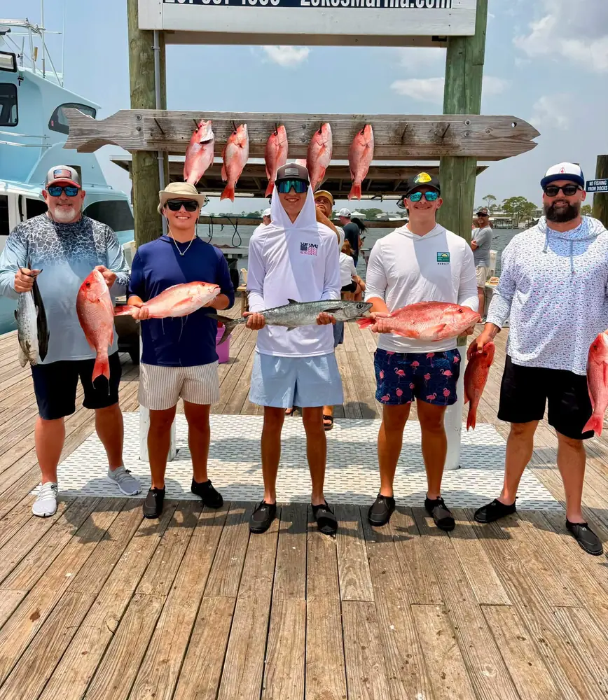 Four anglers holding red snapper on the dock