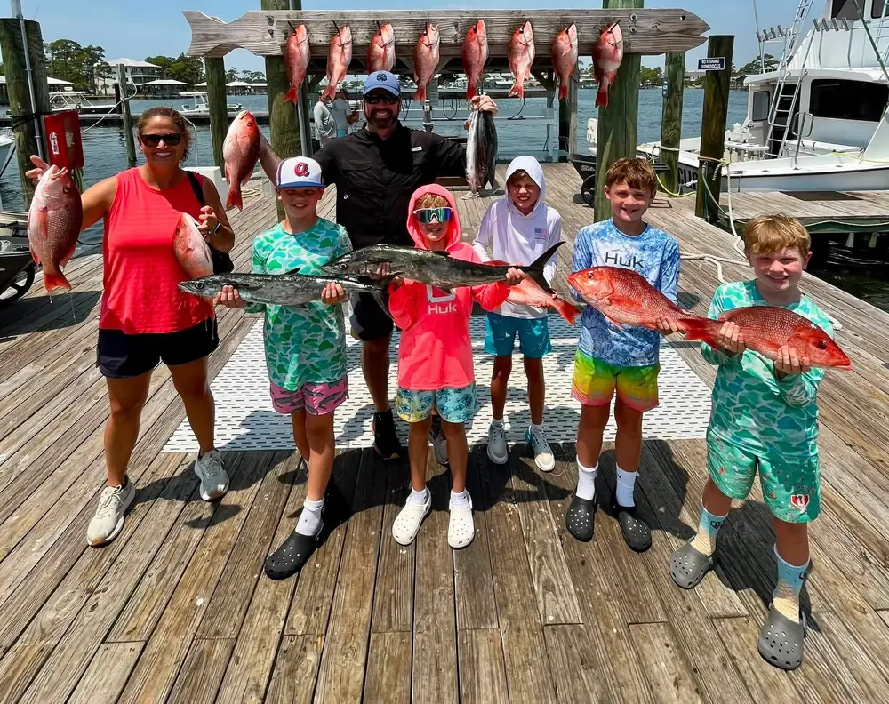 A family group with kids and their snapper on the dock