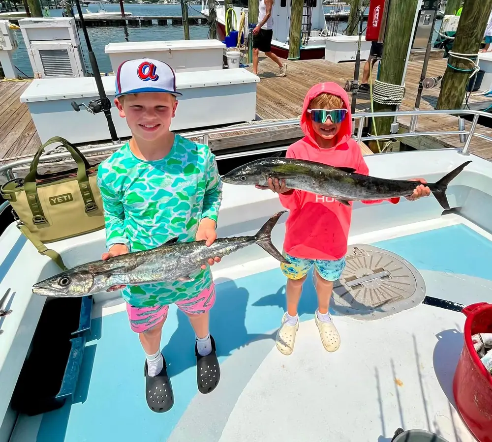 A young angler on the boat with a king mackerel