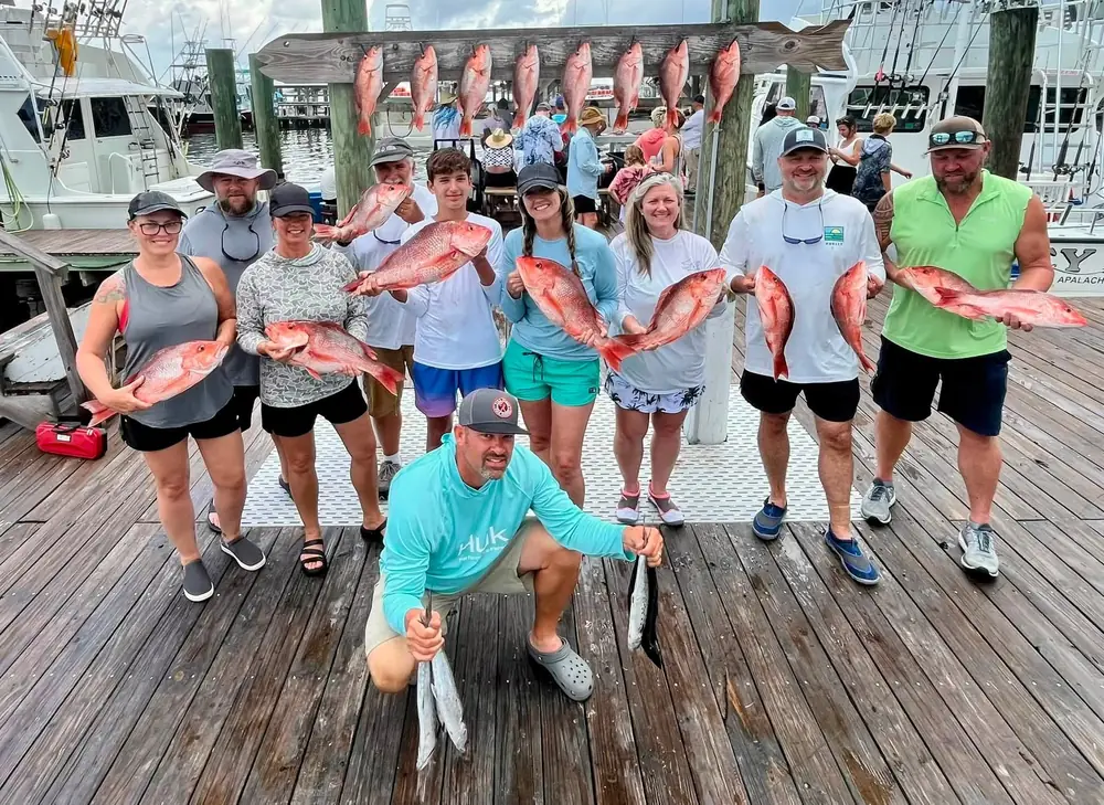 Guests holding their red snapper on the Orange Beach dock