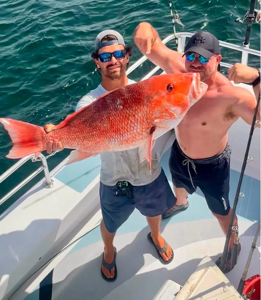 An angler holding a heavy red snapper aboard the boat