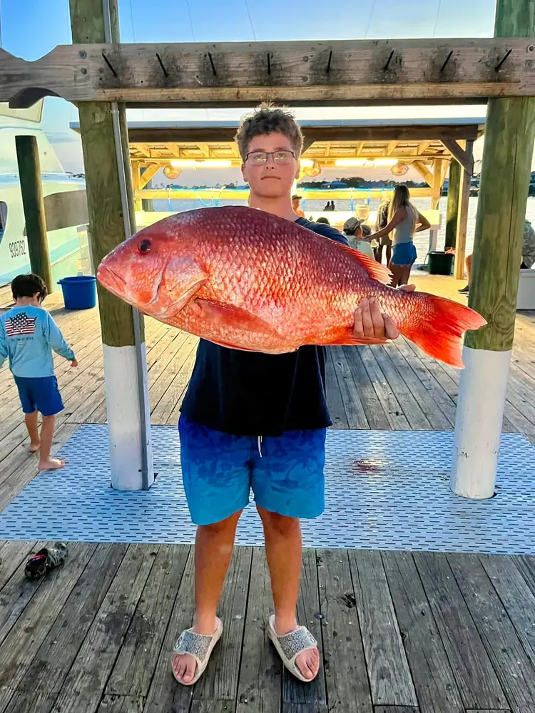A young angler with a big red snapper at the dock