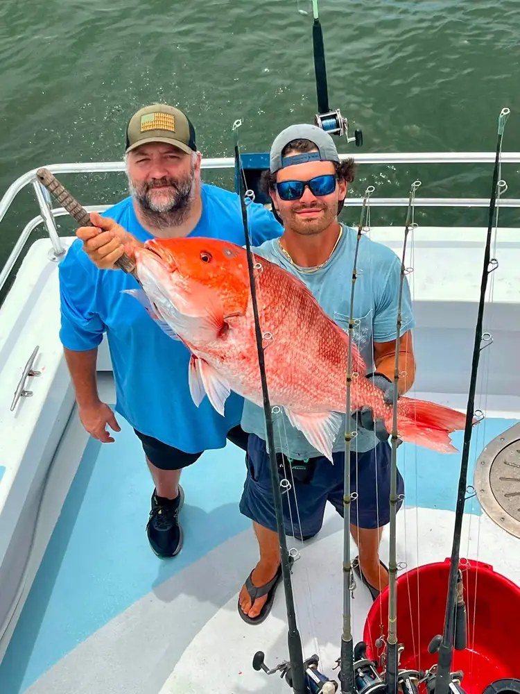 Two anglers with a red snapper on the back deck