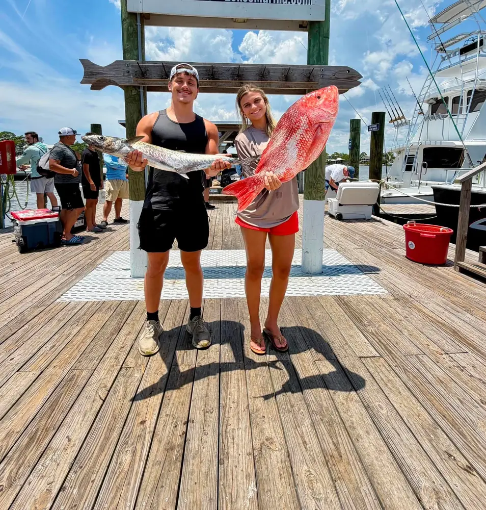 Two guests holding a big red snapper on the dock