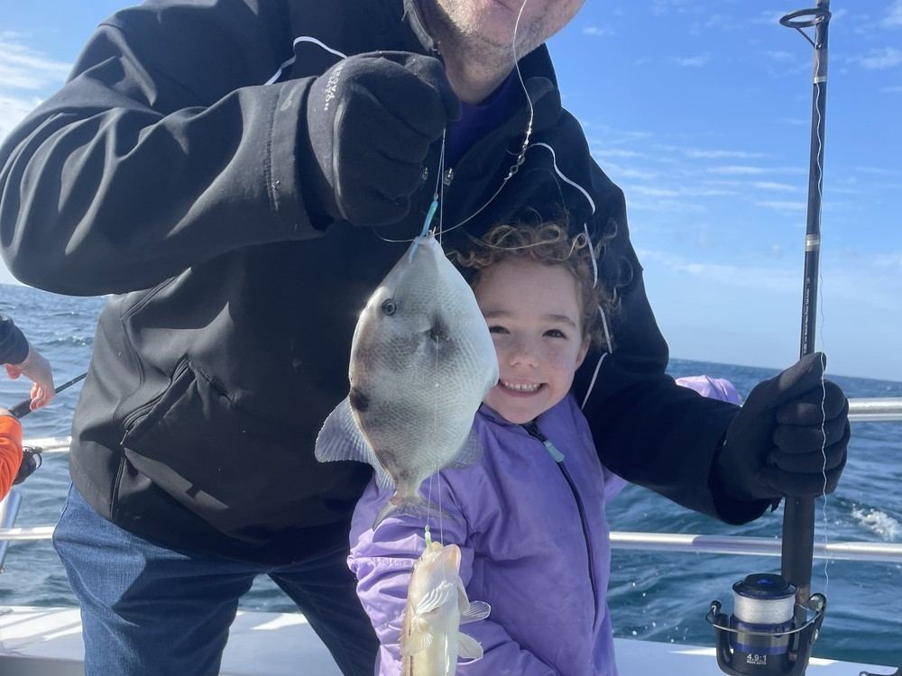 A young angler proudly holding her first triggerfish