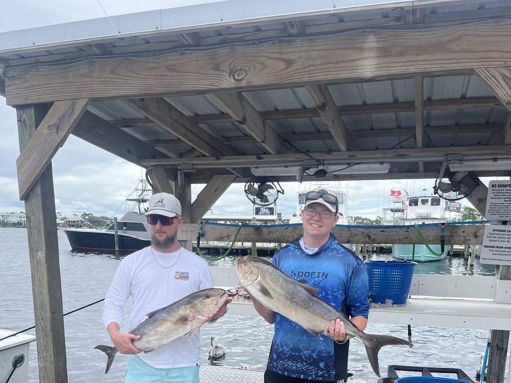 Two guests with an amberjack on the dock in Orange Beach