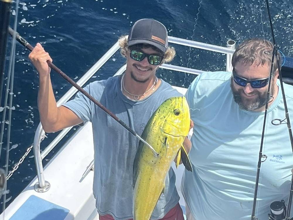 Two anglers with a bright mahi caught on the troll