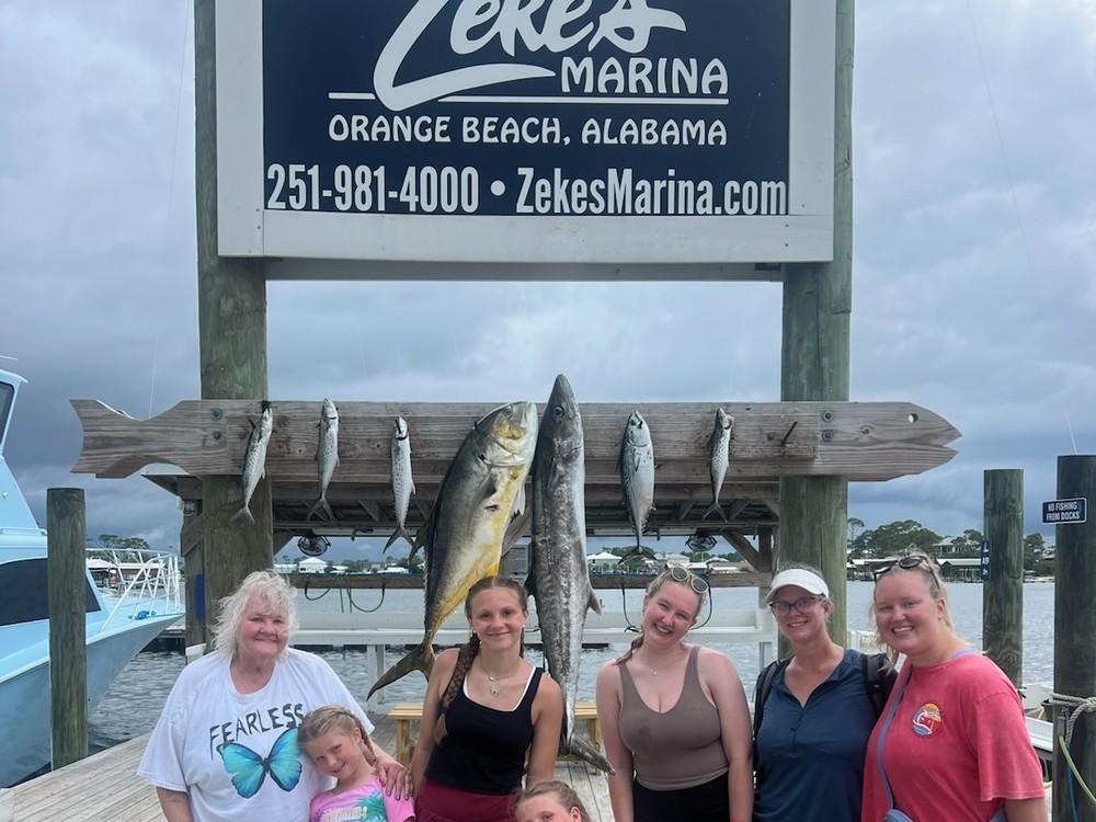 A family group with their catch under the Zeke's Landing sign