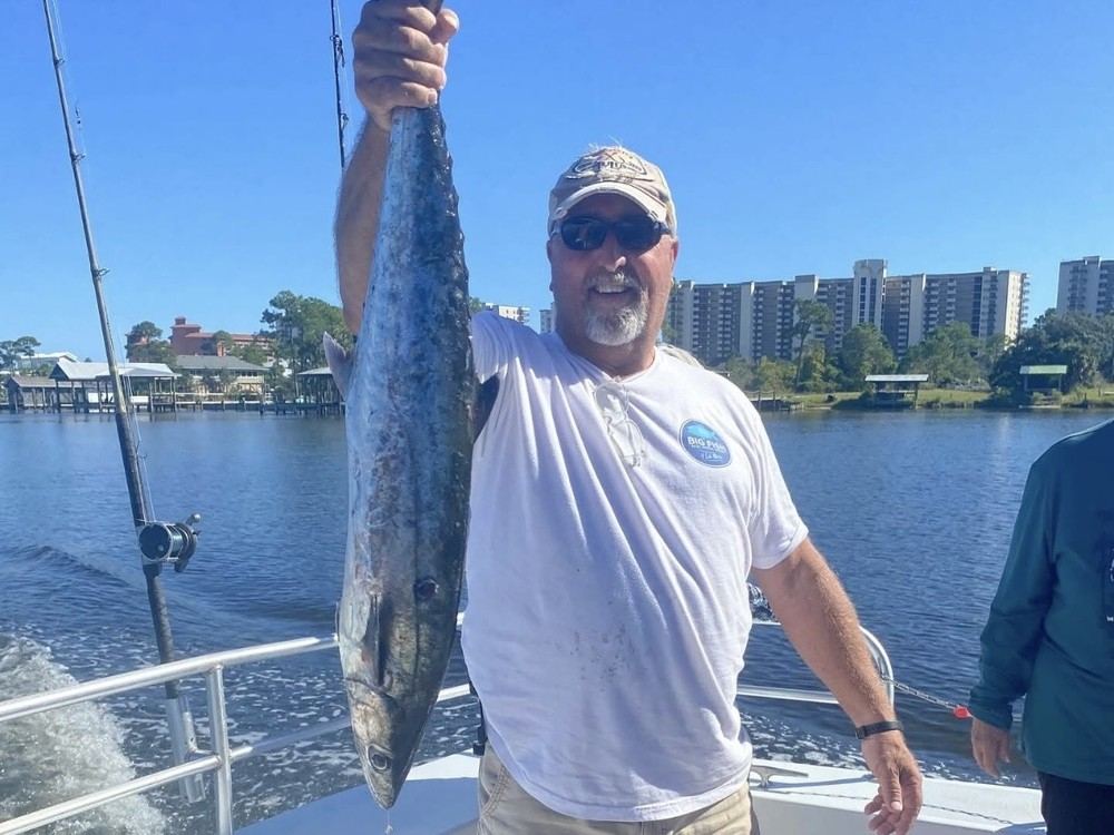 A guest holding a long king mackerel caught trolling near shore
