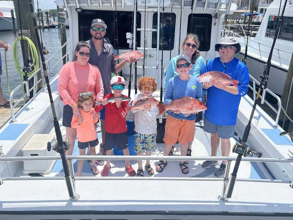 A family group with their red snapper on the stern of the Rip Tide